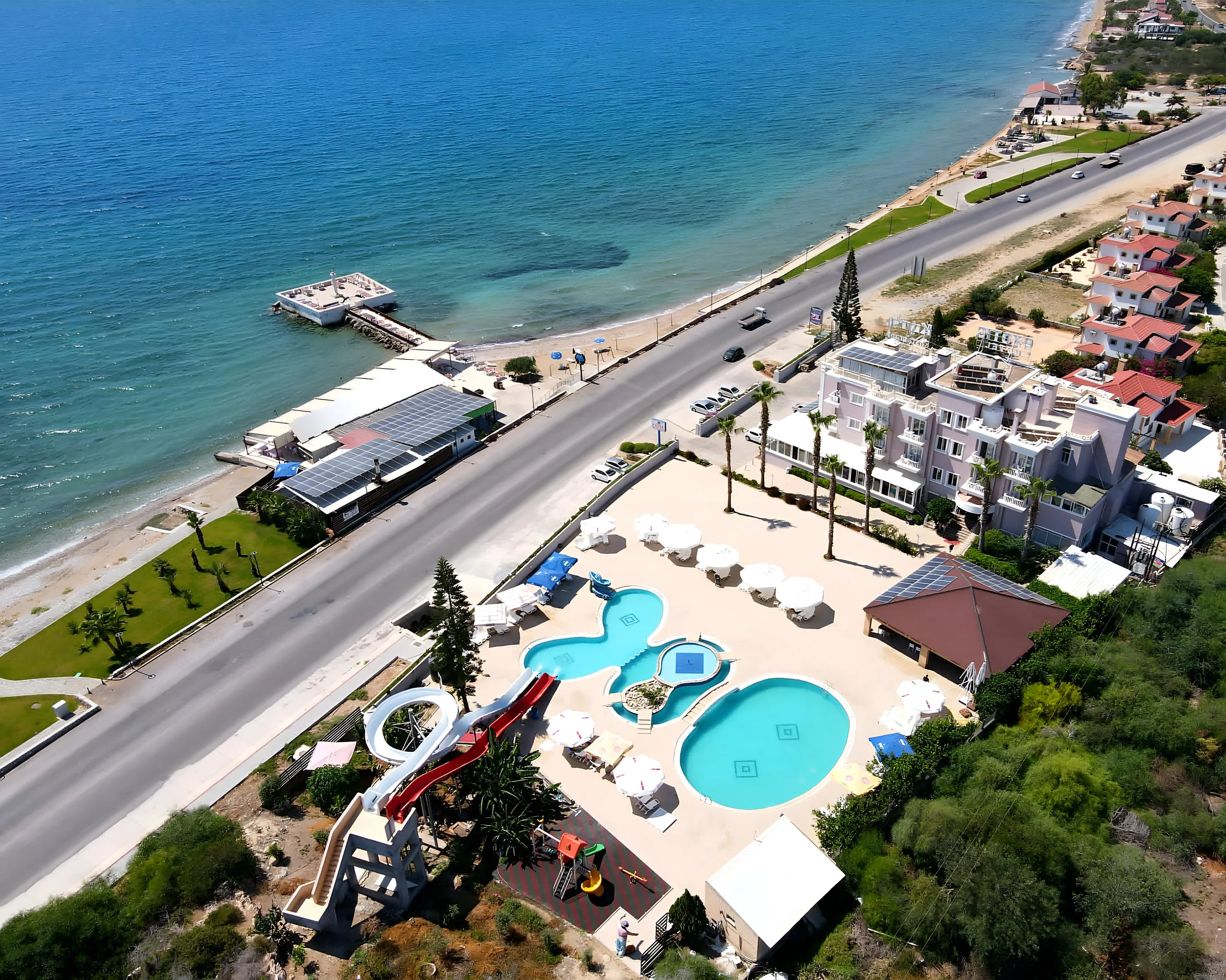 Aerial view of the hotel, its pools and the coast road beside the sea